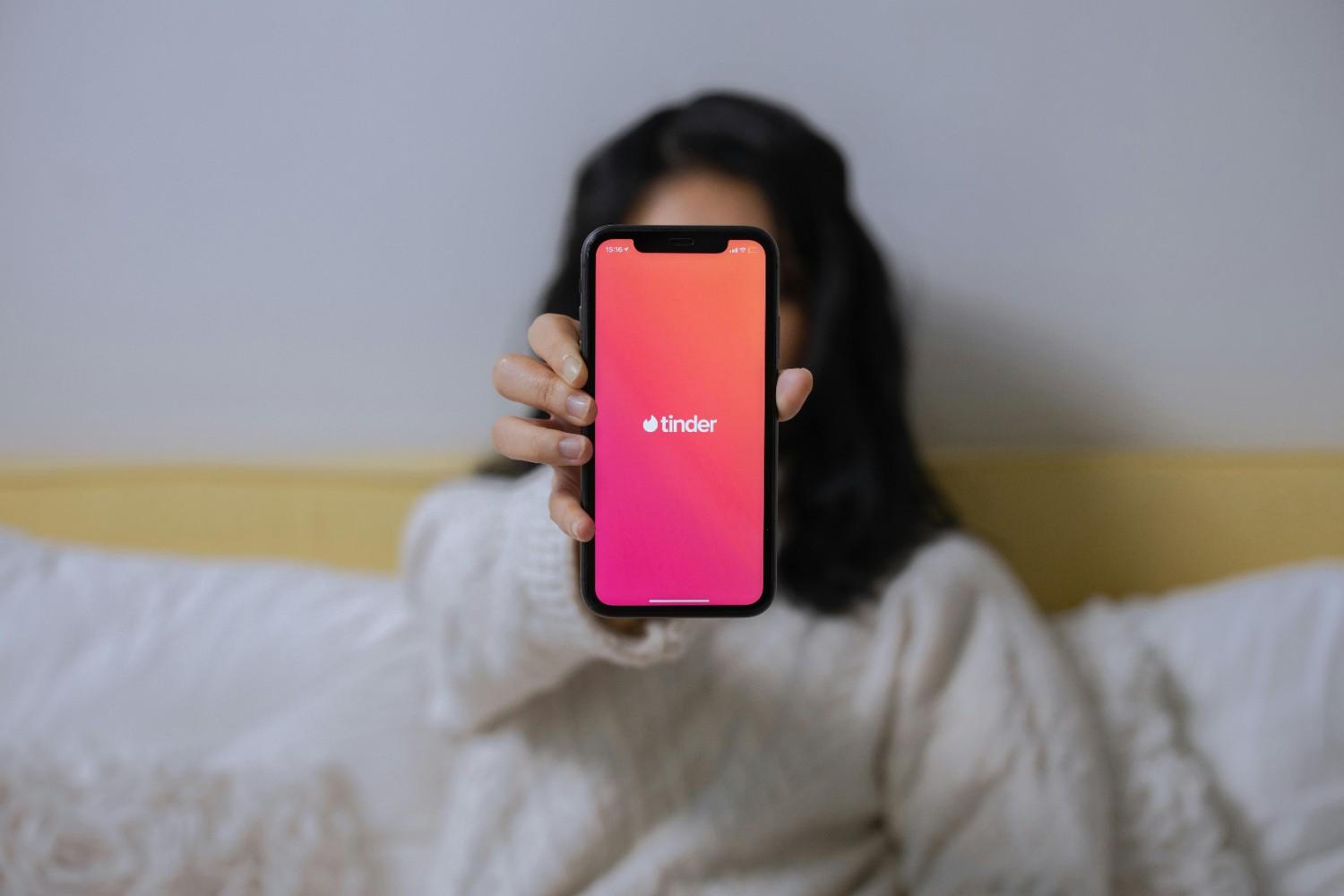 Tinder logo with phone displaying verification code entry screen and dating profile setup blocked by verification